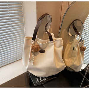 Détail du sac cabas en toile avec poignées en cuir marron et pendentif ours peluche