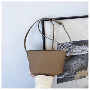 Detailed macro view of the brown lychee grain leather texture on the bucket crossbody bag