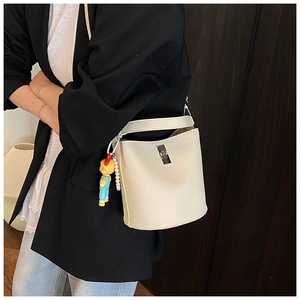 Detail of off-white bucket bag with pebble leather, metal lock and pearl charm