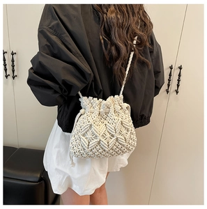 Detail of hand-woven cream bucket bag featuring geometric crochet patterns and drawstrings