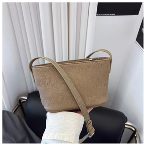 Detail view of khaki pebbled leather bucket bag with metallic zipper and slim shoulder strap