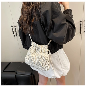 Detail of white hand-woven bucket bag with intricate cutout patterns and drawstring