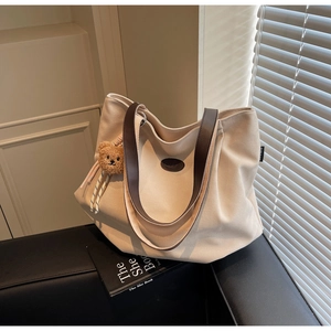 Détail du grand sac cabas en toile beige avec anses en cuir et petit ours en peluche