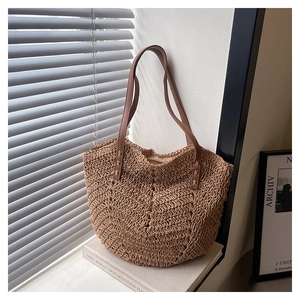 Detail of hand-woven straw tote with V-shaped wave pattern and brown leather straps