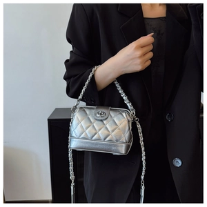 Close-up of a silver quilted chain bag with a metallic finish and twist lock on a model