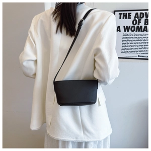 Detail of black pebbled leather bucket bag with adjustable strap worn by a model
