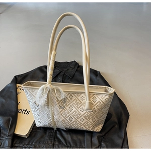 Detail of cream jacquard tote bag with geometric pattern and delicate lace bow