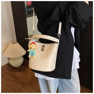 Detail of off-white lychee grain leather bucket bag with silver twist lock and cartoon charm