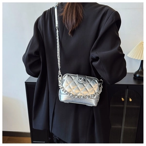 Detailed view of a silver metallic crossbody bag with quilted pattern and chain strap