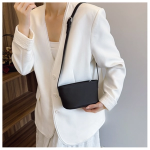 Detail of minimalist black bucket bag with lychee texture and silver hardware on a model