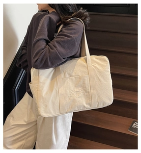 Detail of off-white large canvas tote bag with front pocket and shoulder strap on stairs