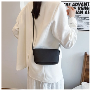 Lifestyle shot of black lychee grain crossbody bucket bag styled with a white blazer