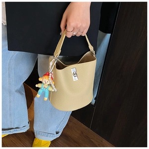 Detail of yellow lychee leather bucket bag with silver turn-lock and pearl doll charm