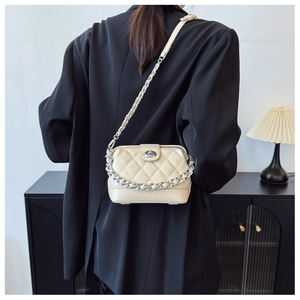 Close-up of quilted crossbody bag with silver chain worn by a model in black blazer