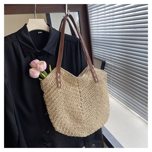 Detailed view of woven straw tote bag with brown leather straps and pink tulips