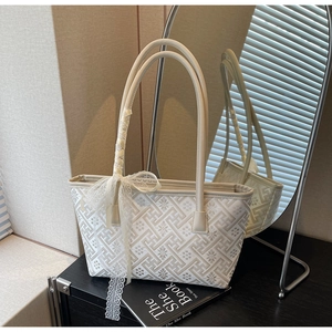 Close-up of beige bucket bag with lace bow and intricate geometric embroidery details