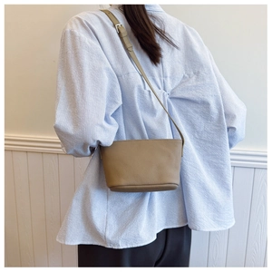 Close-up of khaki bucket bag with lychee grain texture and adjustable strap on a model