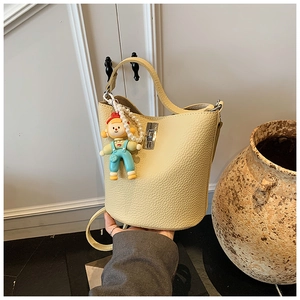 Detail of lychee pattern leather bucket bag in cream yellow with pearl strap and charm