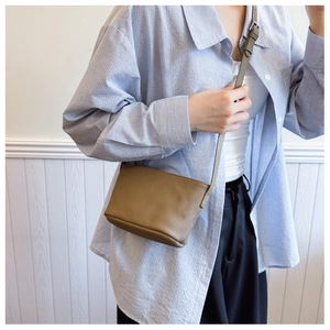 Detail of a brown lychee pattern leather mini crossbody bag with minimalist strap