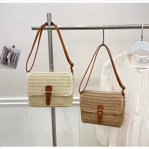 Détail d'un sac bandoulière en paille tressée avec boucle en cuir marron et sangle