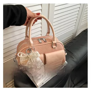 Detailed view of pink woven texture handbag with pearl lace bow charm and silver hardware