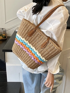Straw woven tote bag with colorful striped base and brown leather shoulder straps