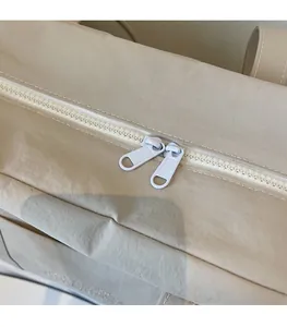 Detail of high-quality smooth dual zipper closure on a beige canvas tote bag