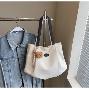 Détail du sac cabas en toile avec lanières en cuir marron et charm ours en peluche