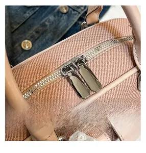 Close-up of double metal zippers and woven texture on a stylish pink handbag