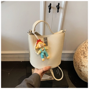 Detail of cream white pebbled leather bucket bag with cute cartoon charm and silver clasp