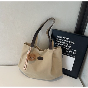 Détail du sac cabas en toile avec garniture en cuir marron et pendentif ours en peluche