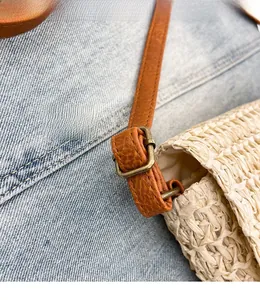 Détail du sac en paille tressé avec bandoulière en cuir marron et boucle en métal vintage