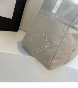Detail of lightweight nylon tote with double heart embroidery and white zipper