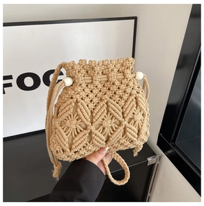 Close-up of beige hand-woven bucket bag with hollow diamond patterns and drawstrings