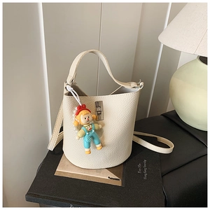 Close-up of cream bucket bag with lychee texture, silver buckle, and cute cartoon charm