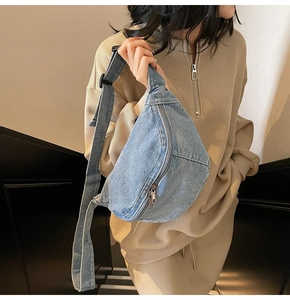 Close-up of light blue denim crescent crossbody bag with adjustable strap and metal zipper
