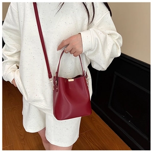 Detail of burgundy bucket bag featuring gold metal clasp and matte leather texture