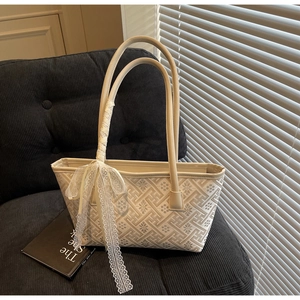 Detailed embroidery texture on beige vintage bucket bag with elegant lace ribbon decoration