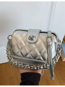 Silver quilted crossbody bag with metal chain detail and retro clasp in a minimalist room