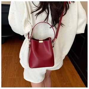 Model view showing a vintage burgundy bucket bag with gold hardware and top handle