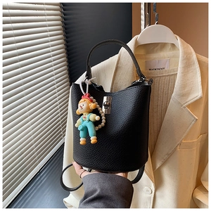 Close-up of black pebble leather bucket bag featuring a silver lock and pearl doll charm