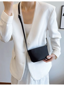 Minimalist black lychee pattern crossbody bucket bag worn with elegant white blazer