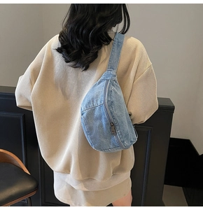 Close-up of the light blue denim fabric texture and smooth metal zipper on the chest bag