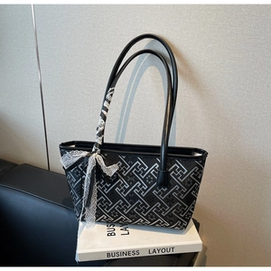 Detail of black and gray geometric tote bag with white lace ribbon and leather handles