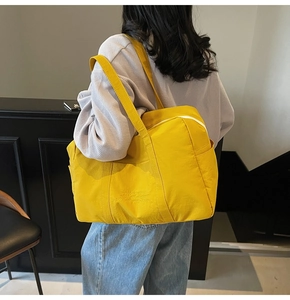 Close-up of bright yellow canvas tote bag with embossed text worn by a model
