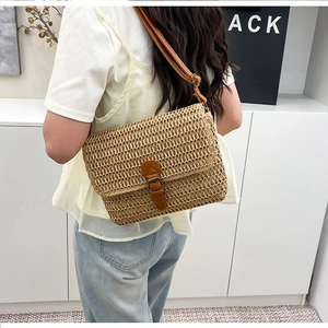 Détail du sac bandoulière en paille tressée avec lanière en cuir marron porté par mannequin