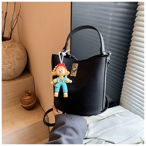 Close-up of black lychee leather bucket bag with silver twist lock and cute doll charm