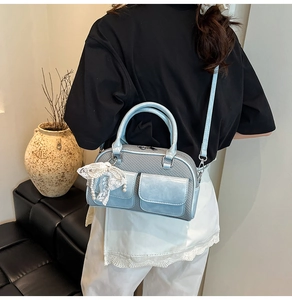 Detail of light blue bowling bag featuring grey woven texture and pearl lace charm