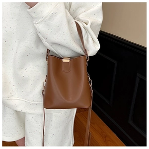 Detail of caramel leather bucket bag with gold metal buckle and versatile shoulder strap