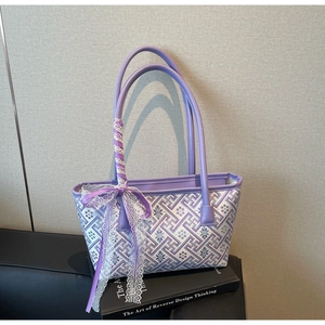 Detail of purple jacquard tote bag with elegant lace ribbon bow and leather handles